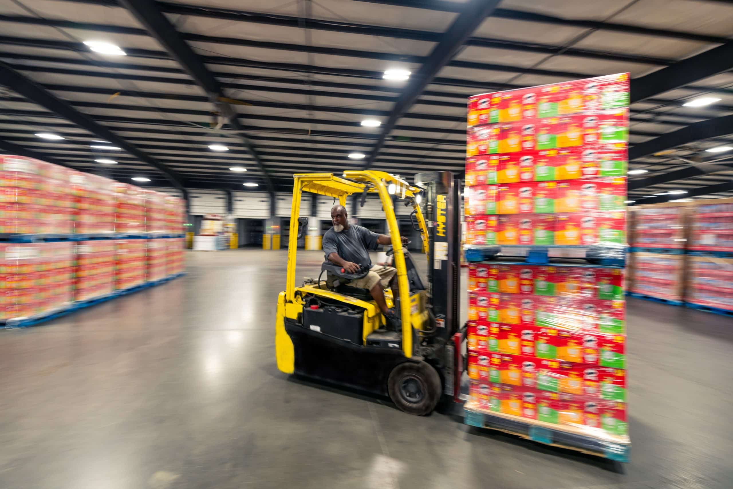 yellow forklift moving a full load of colorful packages - Distribution Technology
